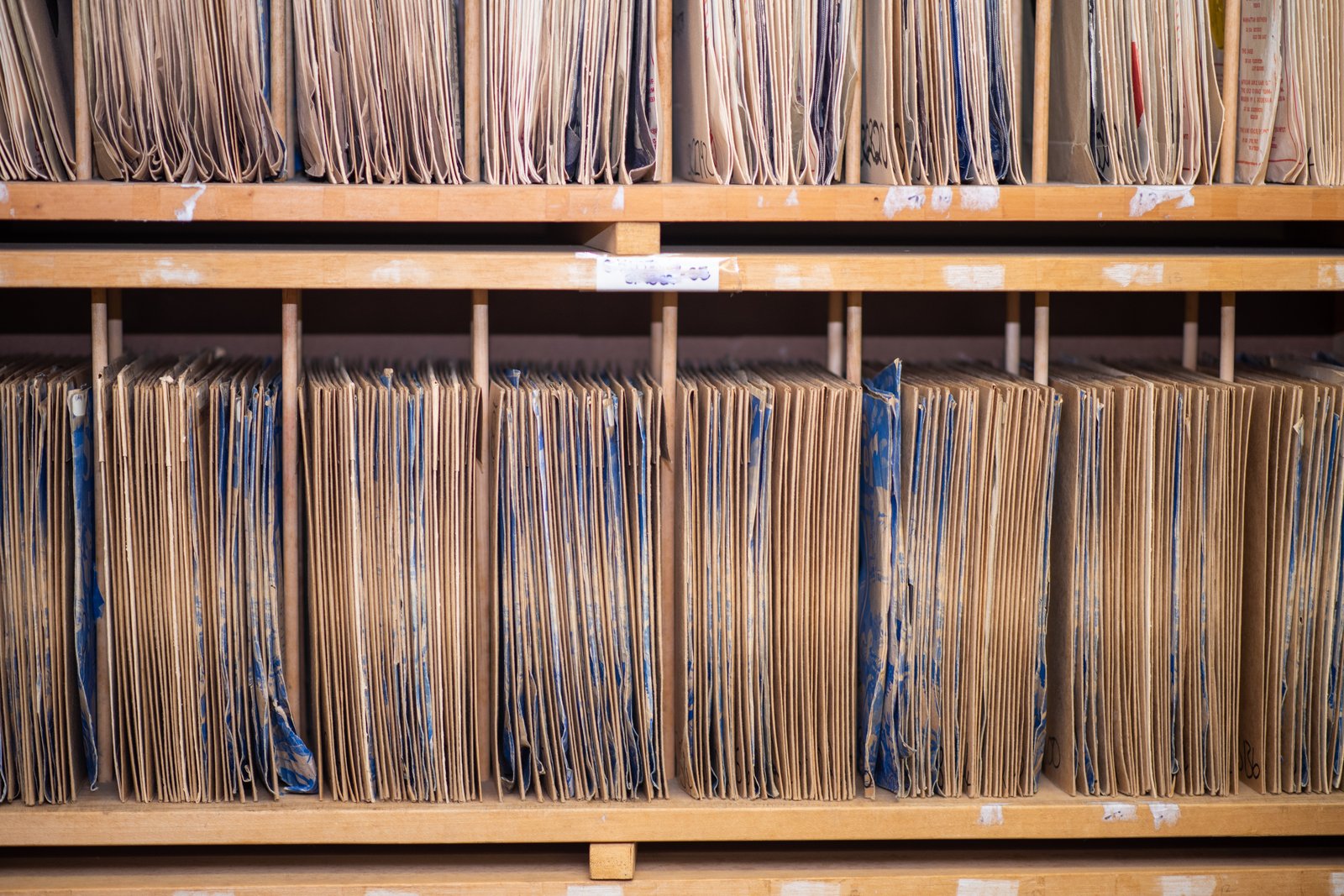 Conservazione digitale a norma: scaffali di archivio storico pieni di fascicoli cartacei