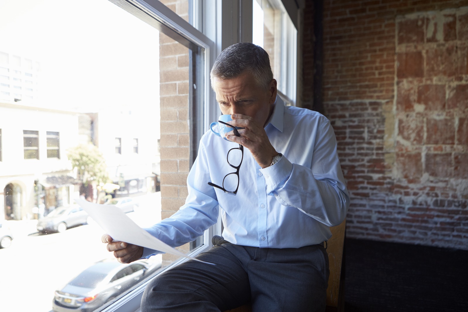 Group treasury: a finance director reading a bank statement by the office window